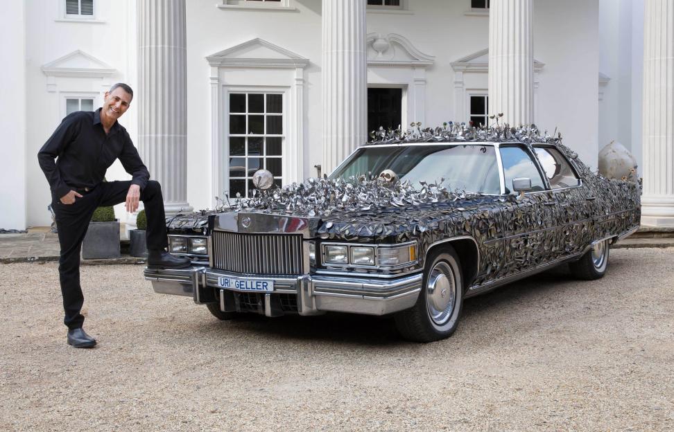 Uri Geller standing by his spoon-encrusted 1976 Cadillac.
