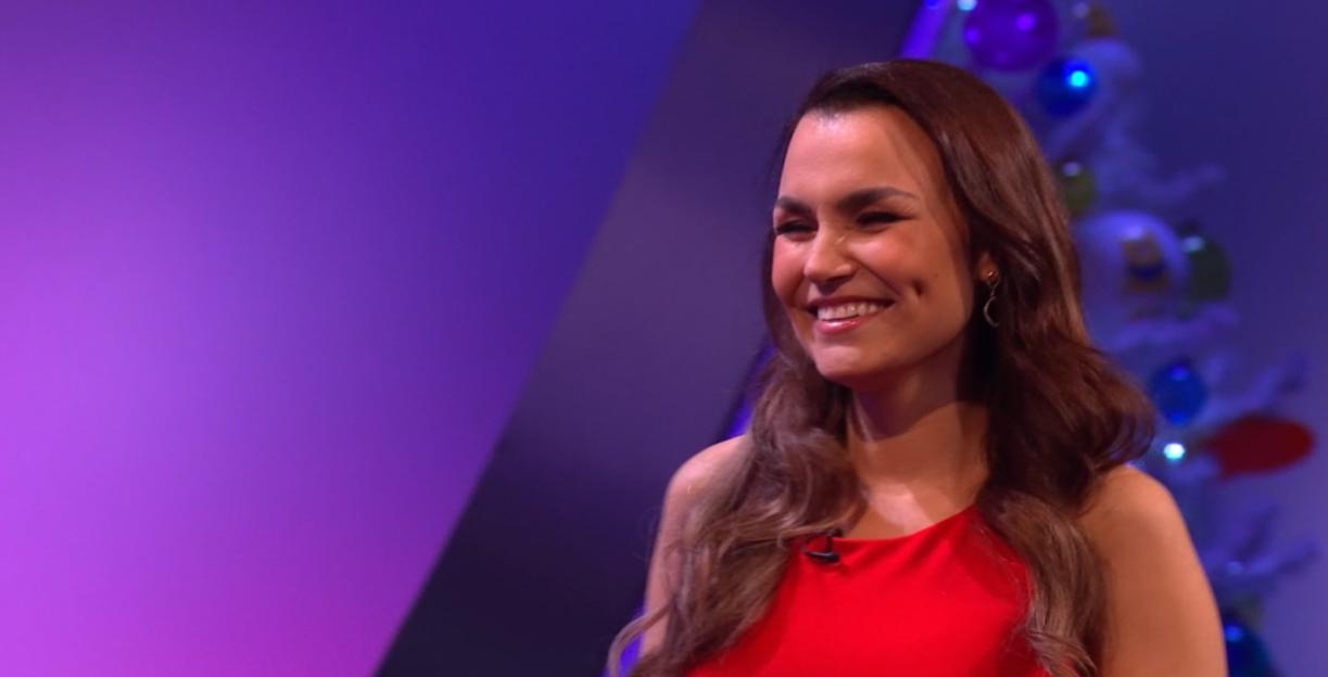 Woman in red dress smiles on game show.