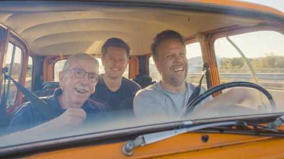 Three men smiling in a car.