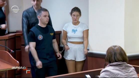 A handcuffed woman in a courtroom.