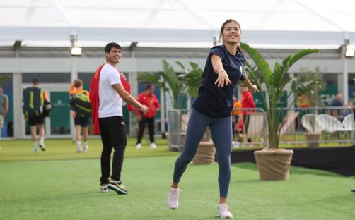 Emma Raducanu warming up, with Carlos Alcaraz in the background.