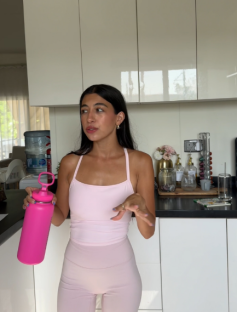 Woman in pink athleisure holding a pink water bottle.