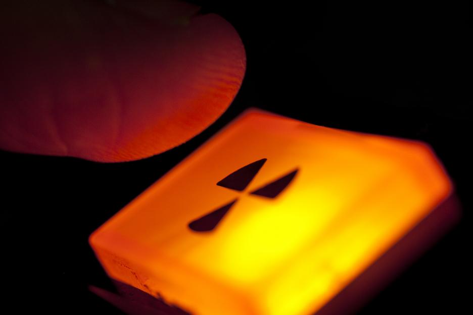 Finger hovering over illuminated radiation symbol.