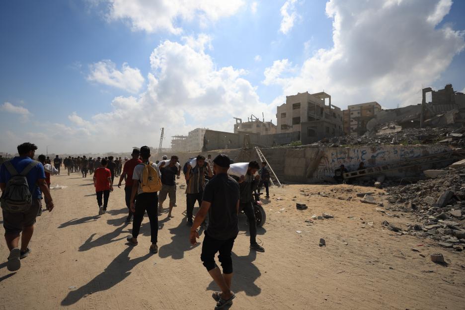 Palestinians carry aid through rubble in Northern Gaza.
