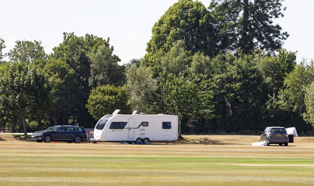 Travellers' caravans and cars parked on a sports field.