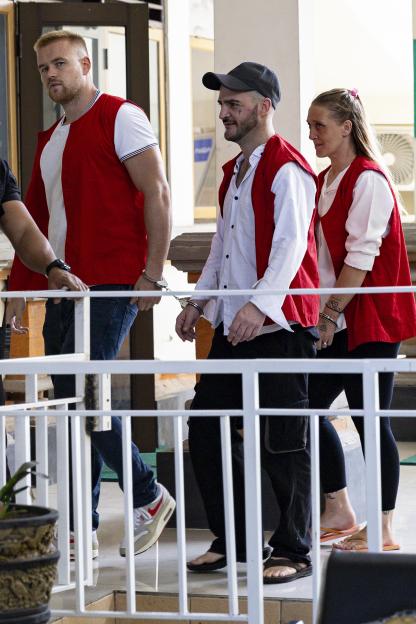 Three handcuffed British drug smuggling suspects walk into a courtroom.