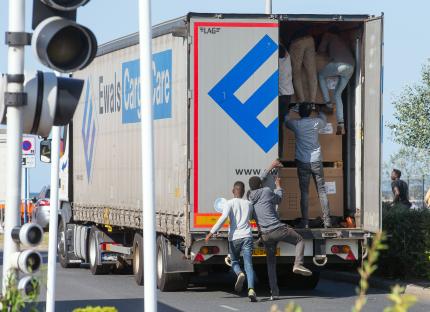 Migrants climbing into the back of a lorry.