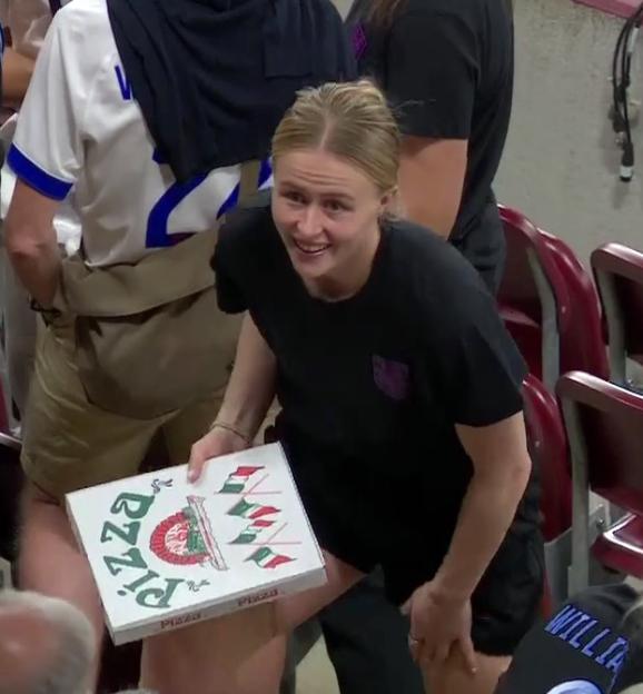 A woman holds a pizza box after a soccer game.