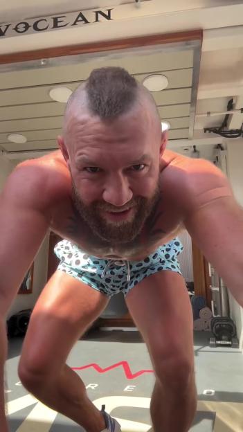 Conor McGregor with a mohawk hairstyle, wearing swim trunks, doing a workout.