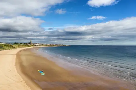 Tynemouth beach with surfboards and a church in the distance.