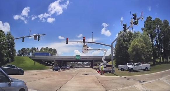 Road crews working on traffic signals at an intersection.