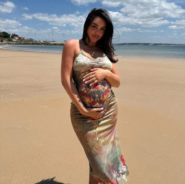 Pregnant Marnie Simpson on a beach.