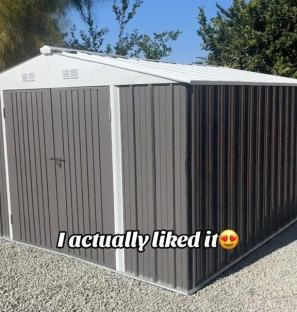 Metal storage shed on gravel.
