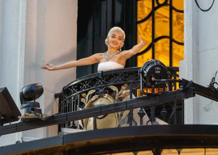 Rachel Zegler on a balcony singing to an audience.