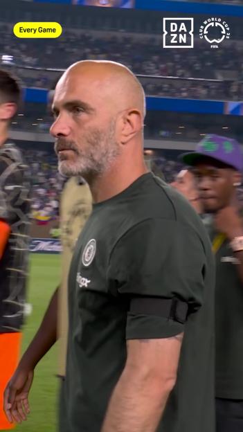 A man in a dark green shirt on a soccer field.