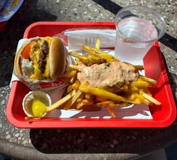 Cheeseburger, cheese fries, and water on a red tray.