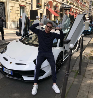 Man posing with a white Lamborghini.