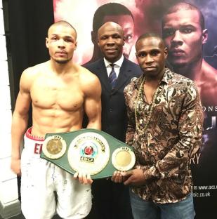 Boxer holding a championship belt with two other men.