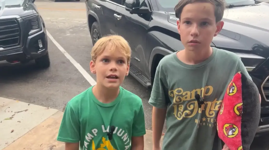 Two boys in Camp La Junta shirts stand outside.