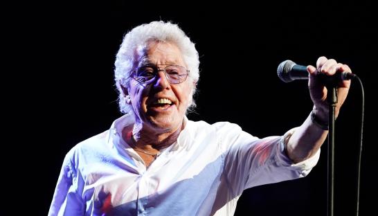 Roger Daltrey singing into a microphone on stage.