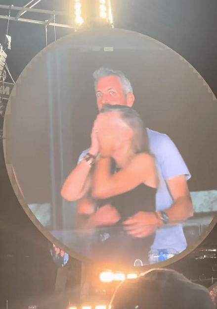 A man and woman embracing on a large screen.