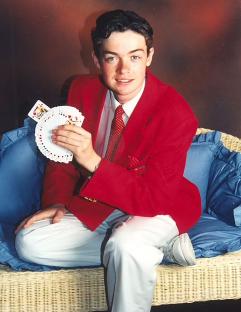 Young Stephen Mulhern in a red jacket, performing a card trick.