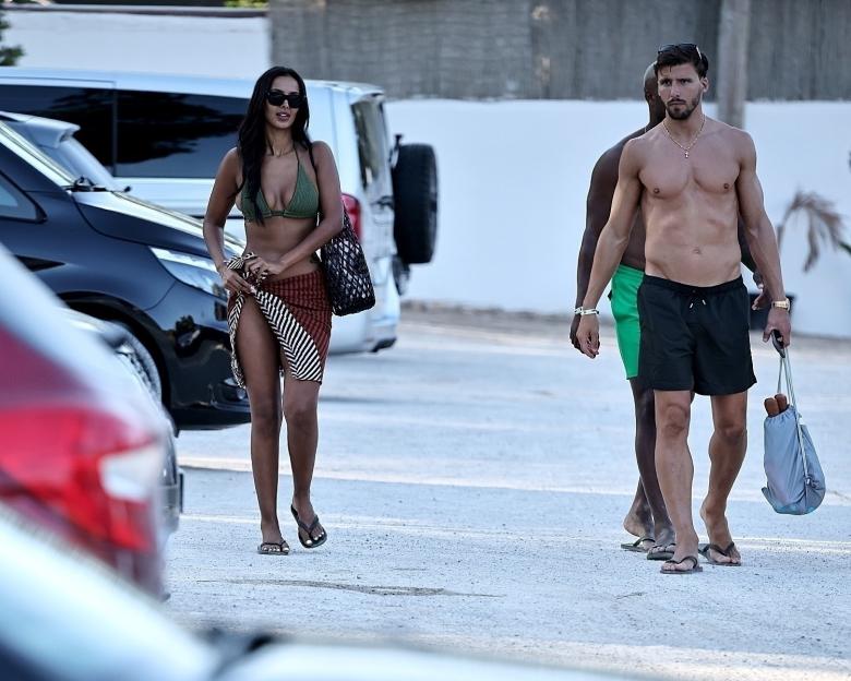 Maya Jama and Ruben Dias walking in a parking lot.