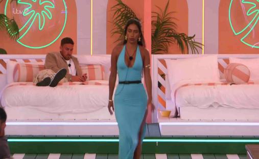 Screenshot from Love Island showing a woman walking away from a man lying on a bed.