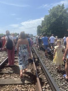 Passengers walking along train tracks after a train breakdown.