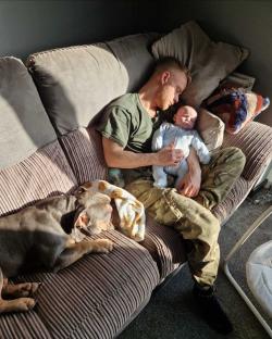 Man sleeping on couch with baby and dog.