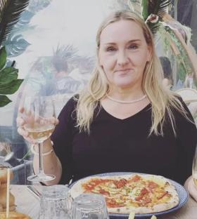 Photo of Jane Riddell enjoying a pizza and wine.