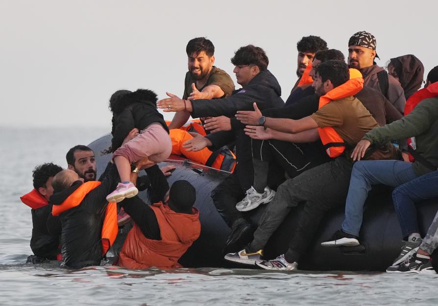 A young girl being lifted into a small boat by a group of people.