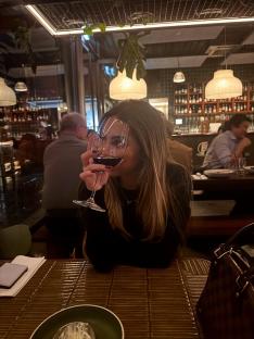 Woman enjoying a glass of red wine at a restaurant.