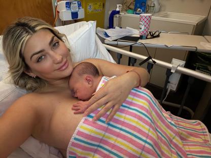 Mother holding newborn baby in hospital bed.