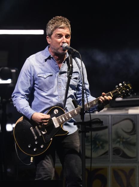 Noel Gallagher playing an electric guitar.