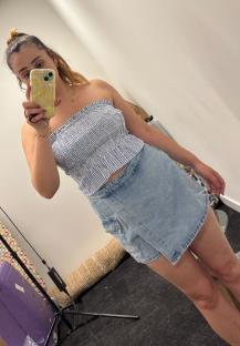 Woman modeling a blue and white striped tube top and light wash denim skirt.