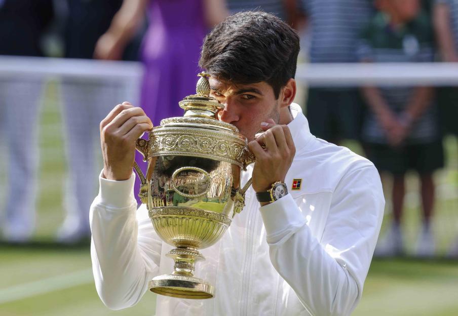 Carlos Alcaraz kissing the Wimbledon Championship trophy.