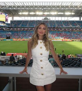 Woman in white dress at a soccer stadium.