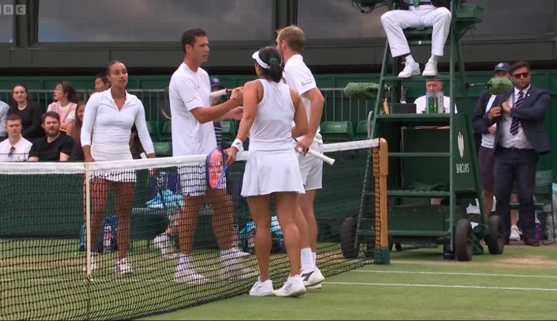 Two women's tennis players shaking hands at the net.