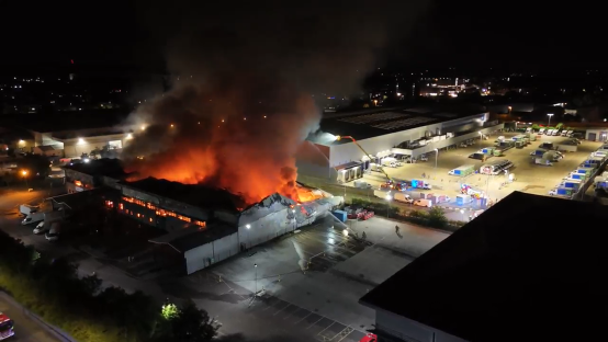 Aerial view of a large building engulfed in flames at night.