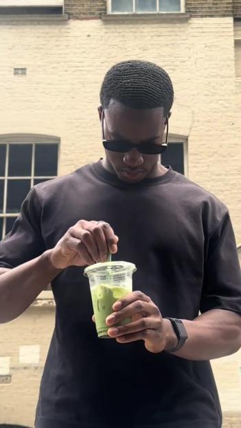 Man holding a matcha iced drink.