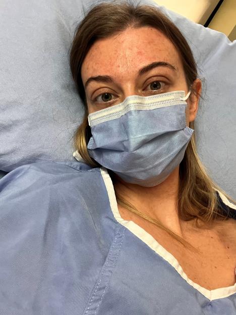 Woman in hospital gown and face mask.