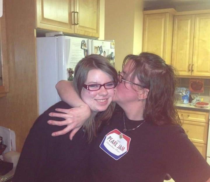 Woman kissing a younger woman on the cheek.