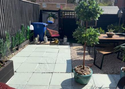 A budget-friendly garden patio with painted slabs, potted plants, and outdoor furniture.