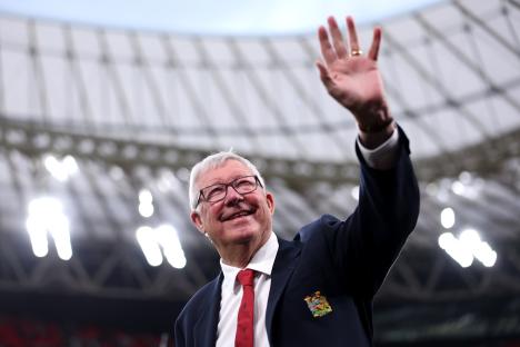 Sir Alex Ferguson waving to fans in a stadium.