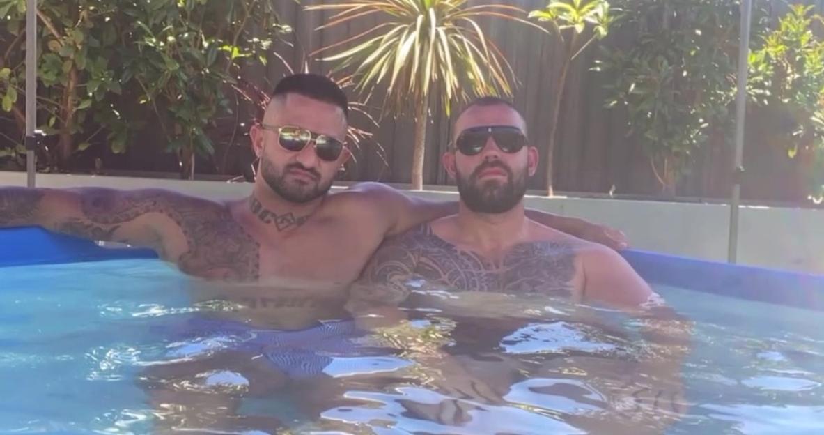Two men with tattoos relaxing in a pool.