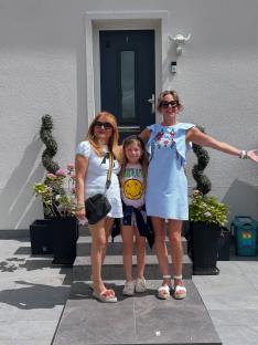 Three women and a girl posing on steps outside a house.