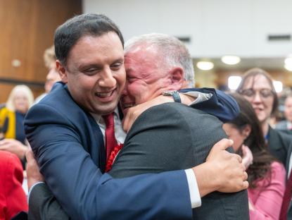 Two men in suits hugging.