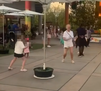 Woman dancing in a public space with children.