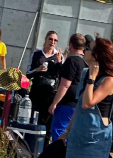 Woman holding a drink, talking to people.